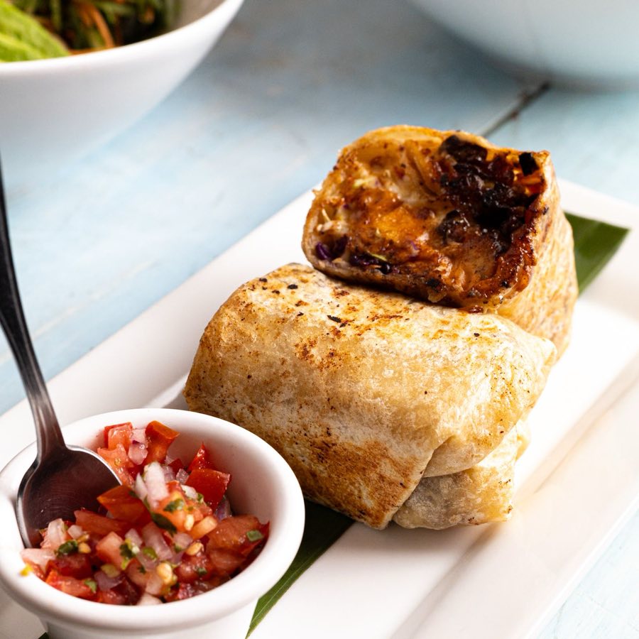A grilled burrito, cut in half, with a side of fresh pico de gallo.
