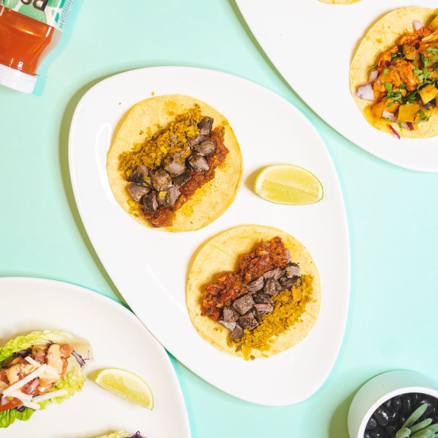 Grilled steak street tacos topped with onion and cilantro, served with a lime wedge.