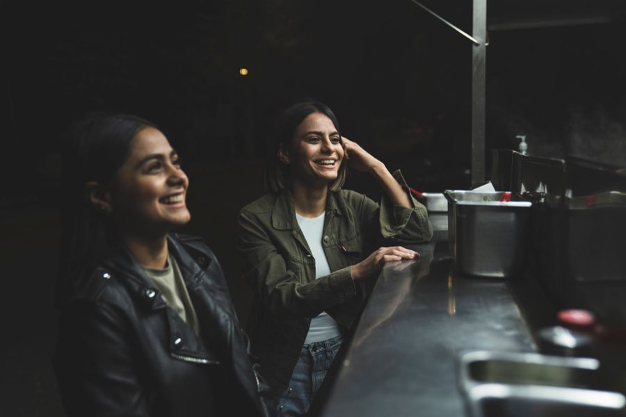 Two regulars laughing at the Mr. Tako counter window.